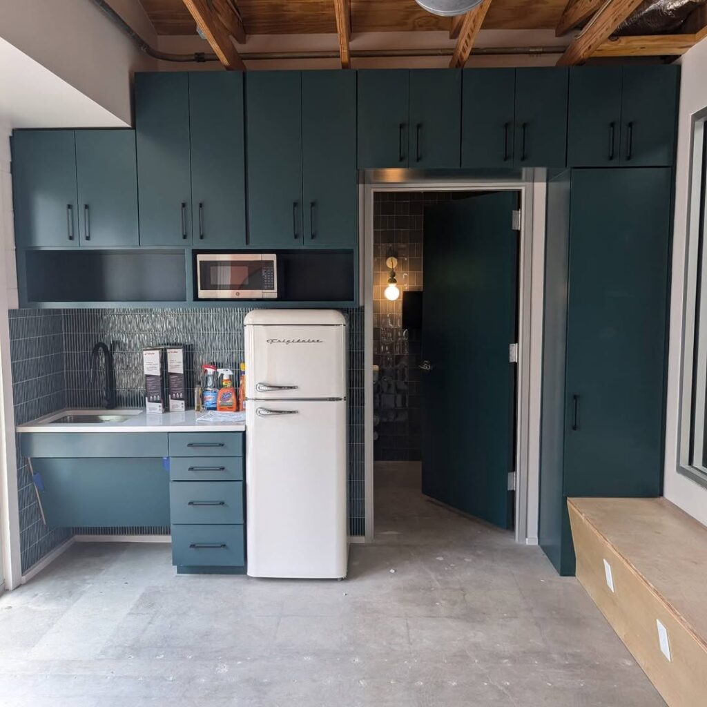 Small commercial kitchen remodel in Austin, TX featuring teal cabinetry, a retro-style white refrigerator, and modern tile backsplash.